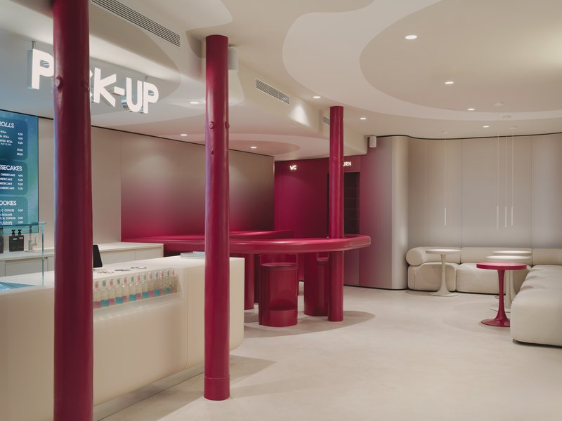 View across the space showing burgundy circular counter with columns and illuminated pickup signage