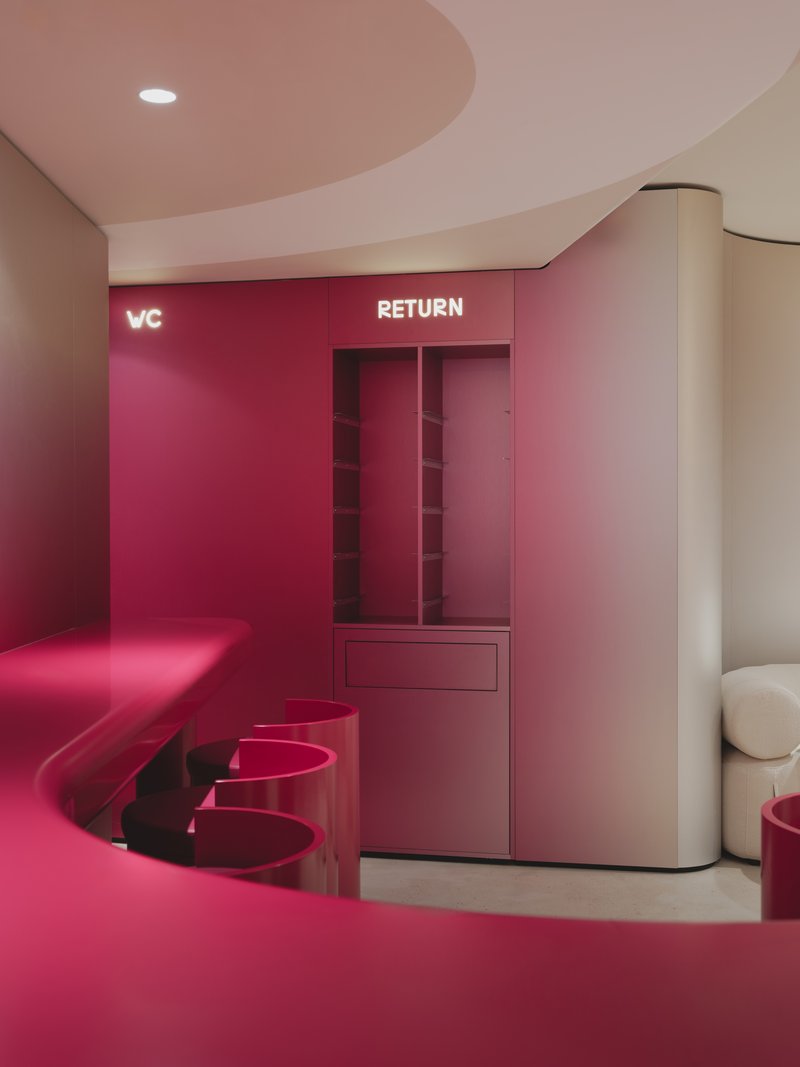 Return station with burgundy millwork, integrated storage cubbies and matching upholstered bench