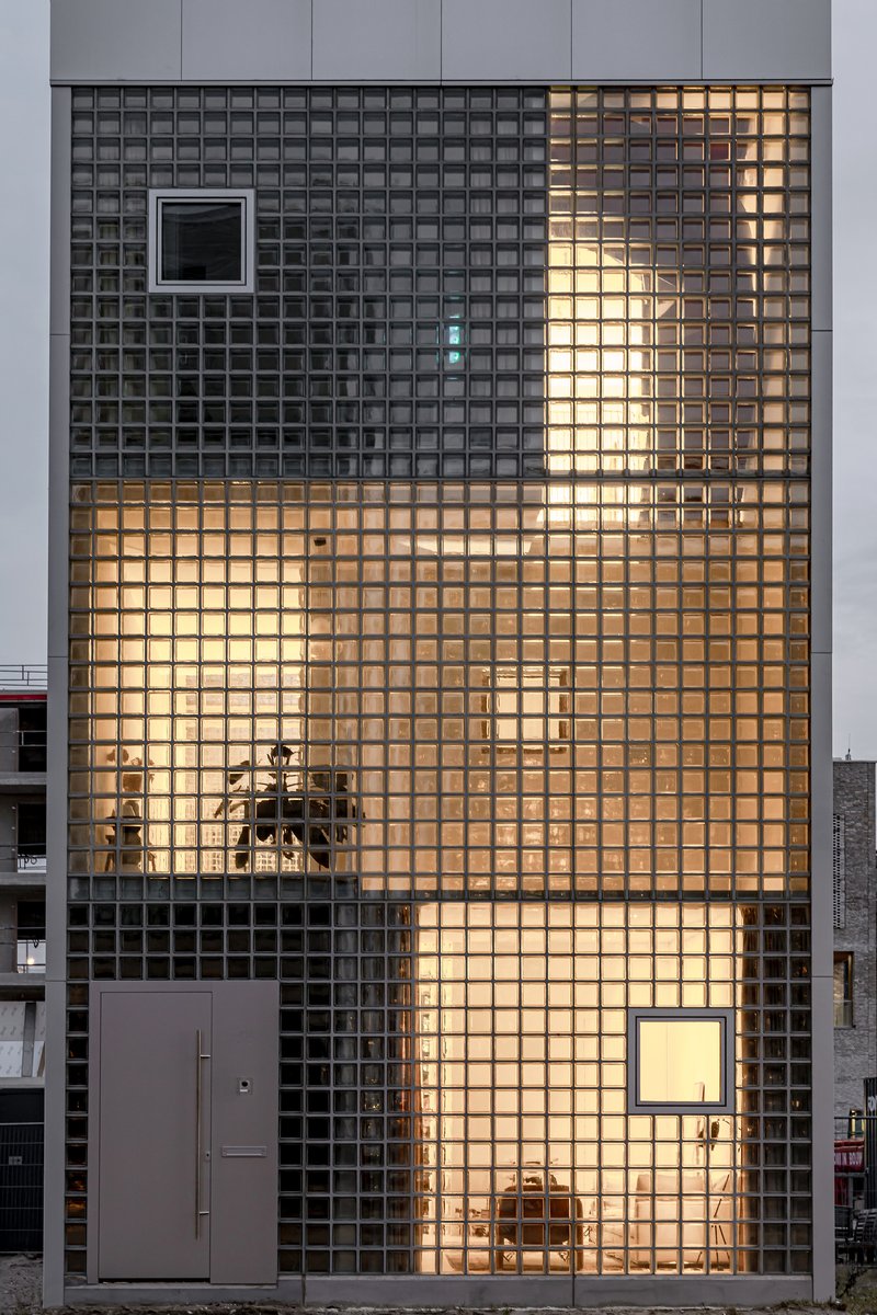 Front elevation of glass block wall with stacked framed openings and interior lighting visible