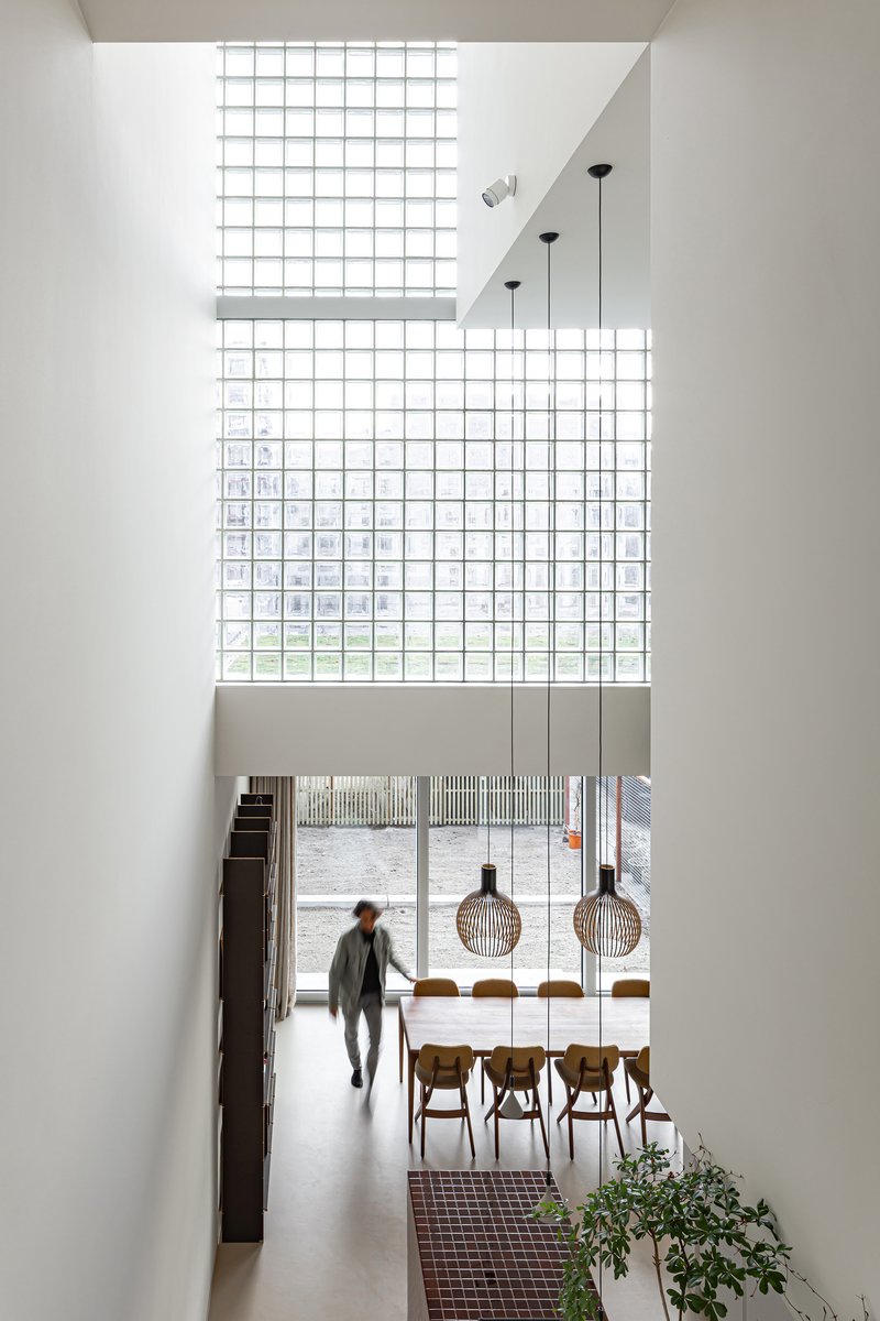 View from upper level showing dining area with pendant lights, glass block clerestory and person walking