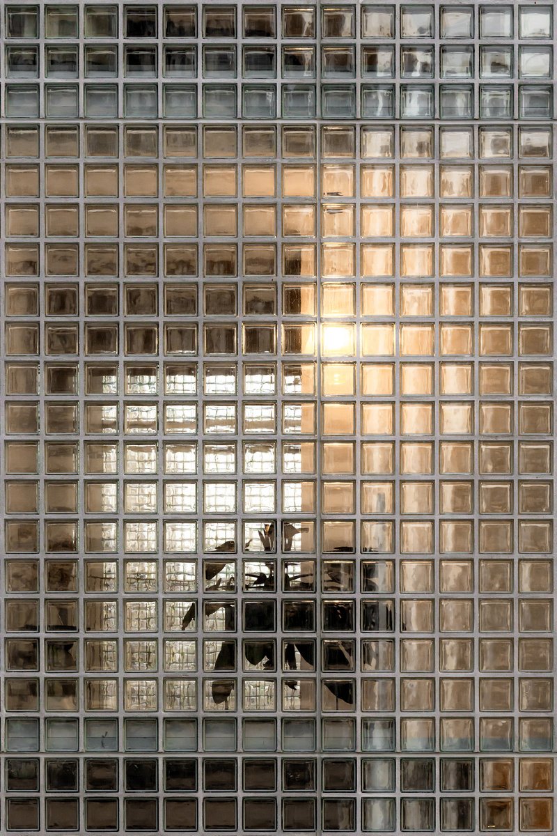 Glass block wall with gridded pattern reflecting warm interior light and exterior view