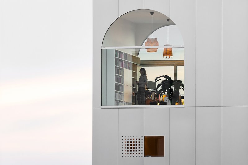 Arched window framing a person in a library workspace with pendant lights overhead