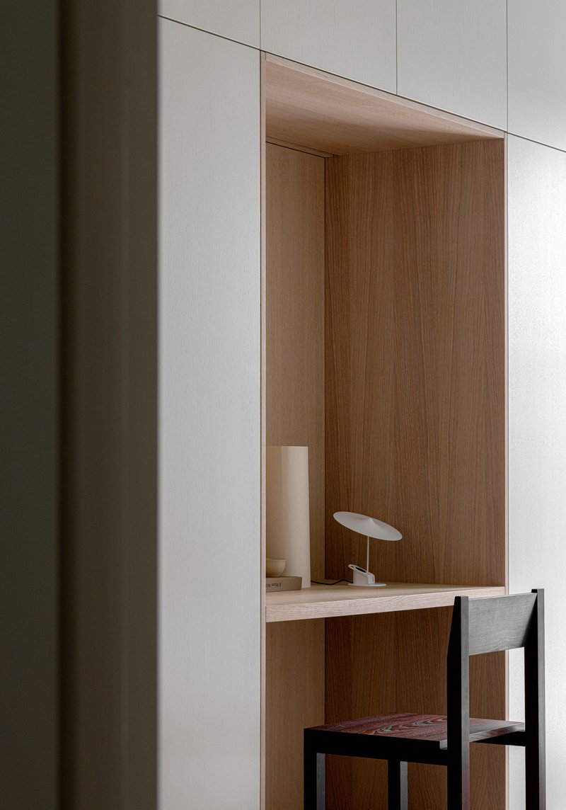 Recessed desk niche with oak veneer interior and white panels framing a simple work surface
