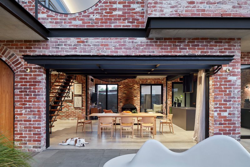 View through brick arches into the dining room with exposed steel beams and polished concrete floor