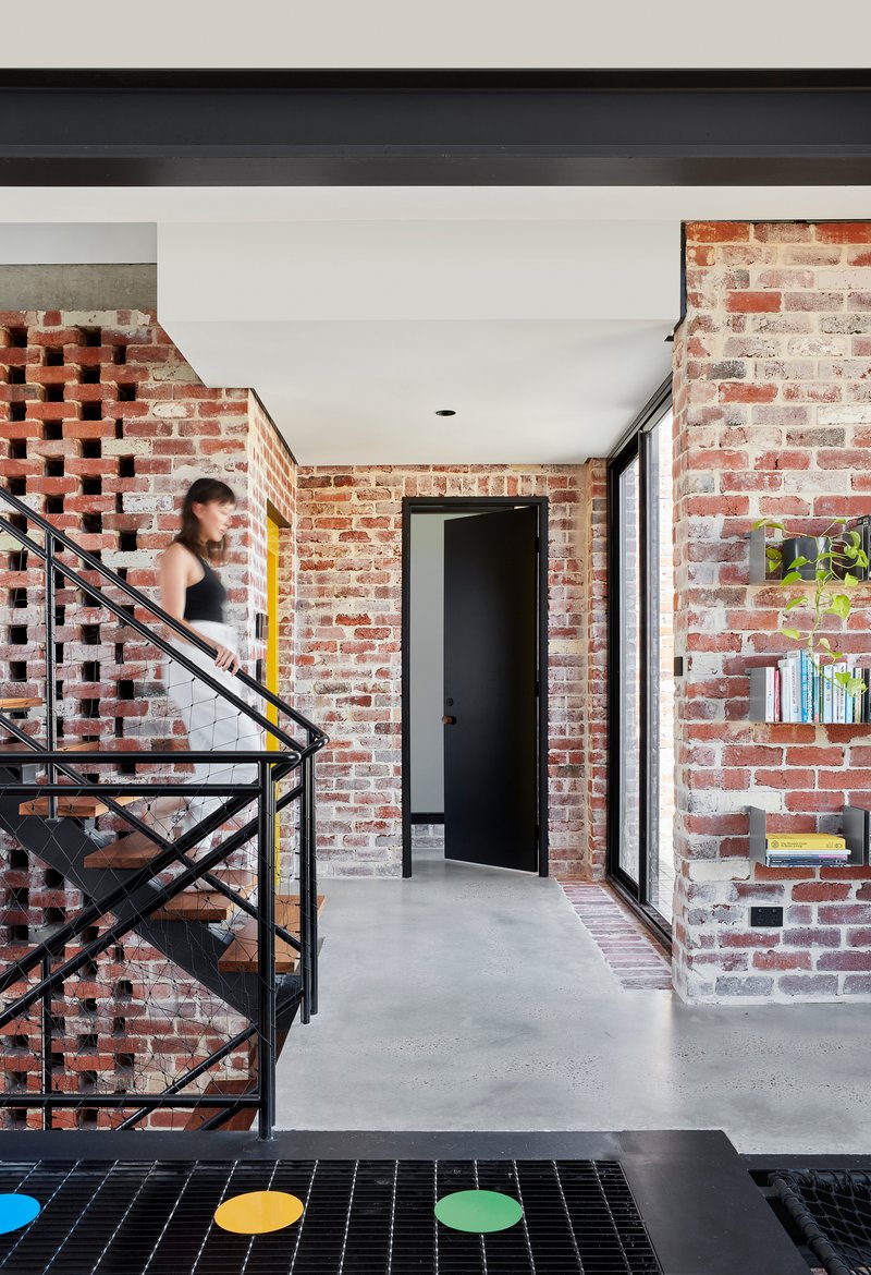 Corridor with perforated brick screen beside the steel staircase and a person descending in motion blur