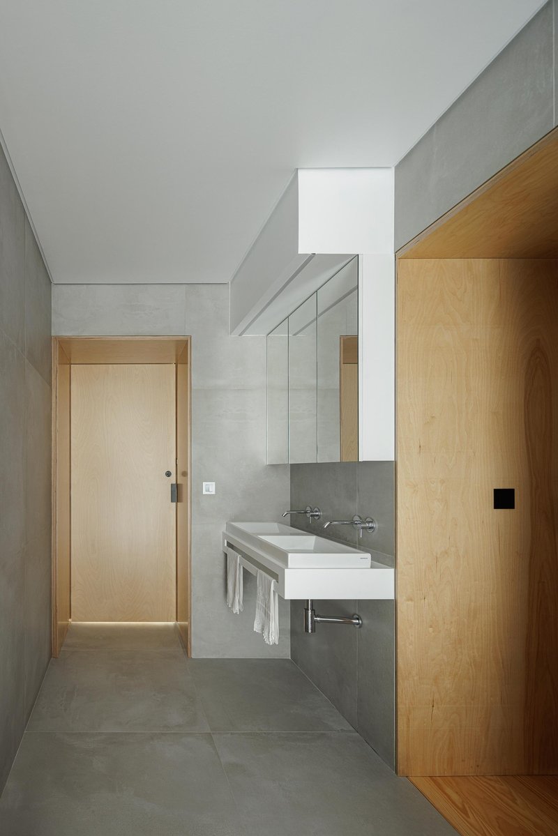 Bathroom interior with concrete walls, skylight above and timber door threshold to bedroom