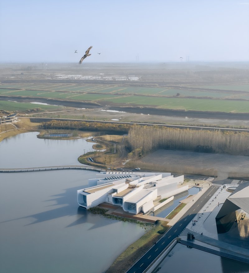 Drone view of the waterside complex with a bird flying above the misty landscape