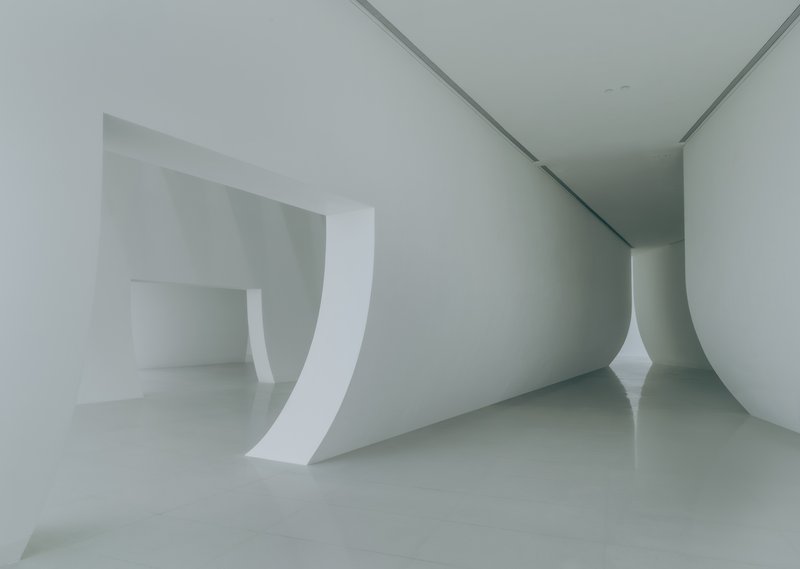 Close-up of the curved white wall meeting the polished floor in the gallery space