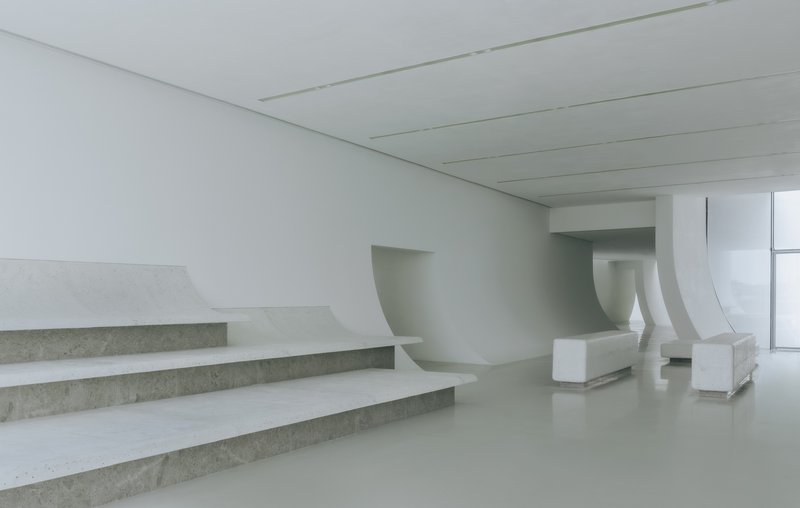 Interior view of the broad staircase with exposed concrete treads and curved white balustrades