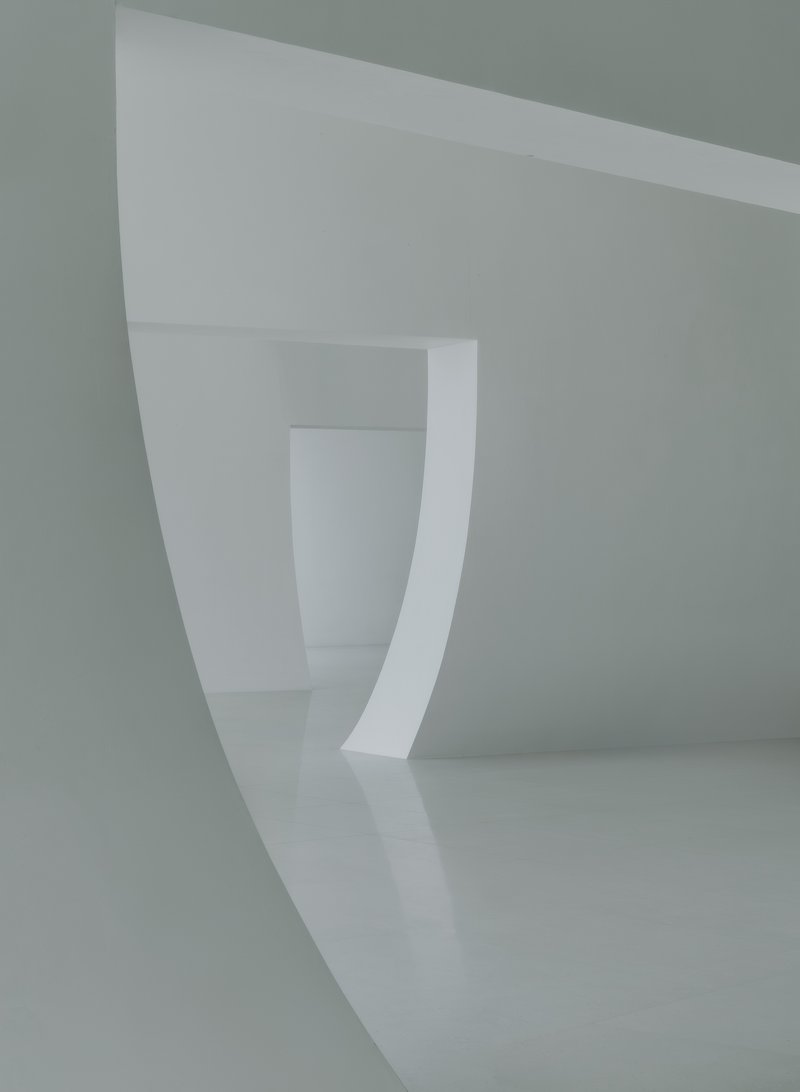 Series of curved white thresholds receding through connected interior spaces under diffused light
