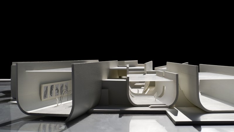Sectional physical model exposing curved interior spaces with sunken amphitheater and terraced levels