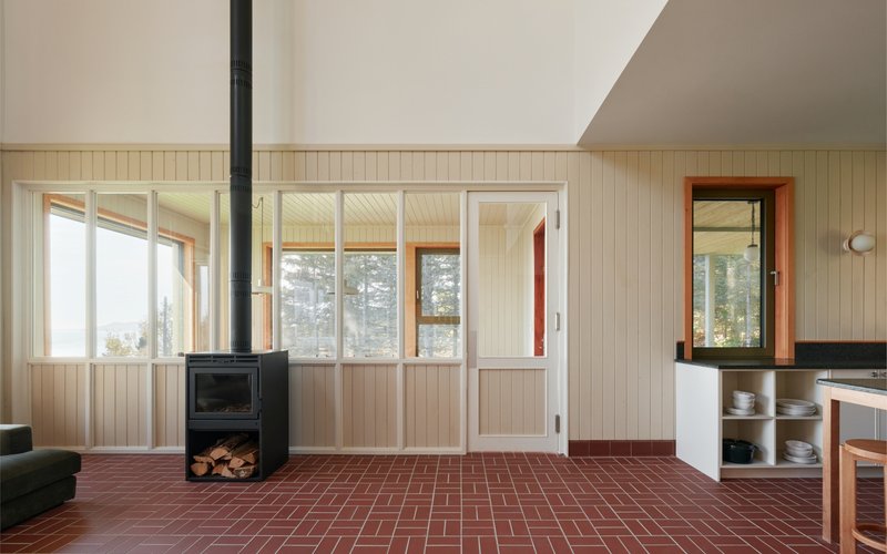 Interior view of wood-burning stove on herringbone brick floor with tongue-and-groove wall paneling
