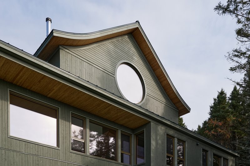 Gabled facade with vertical wood cladding and a large circular window in the upper gable