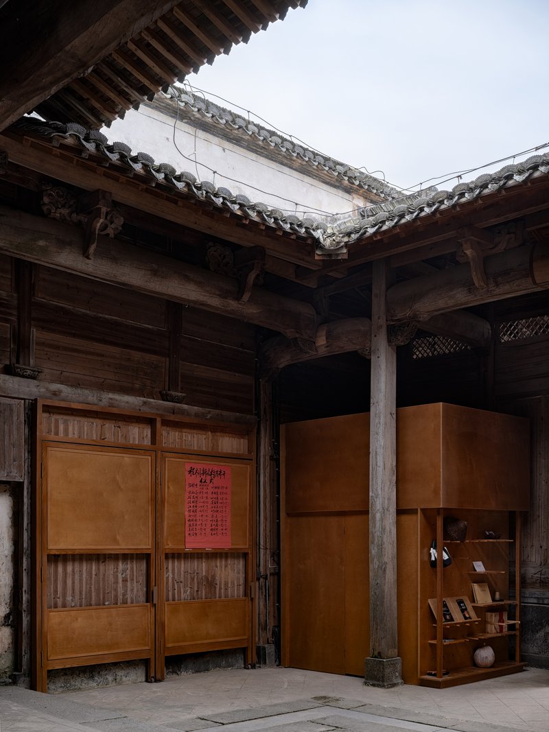Courtyard view with amber exhibition panels set within exposed timber frame structure under traditional tiled roofs