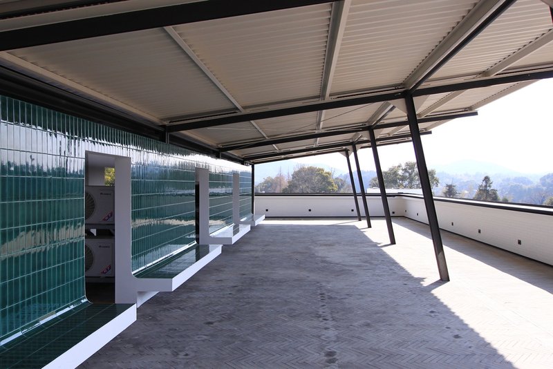 Rooftop terrace with steel-framed canopy, glass brick wall, and white parapet overlooking distant mountains