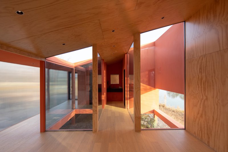 Hallway with wooden ceiling and floor connecting glazed courtyards beneath clerestory openings