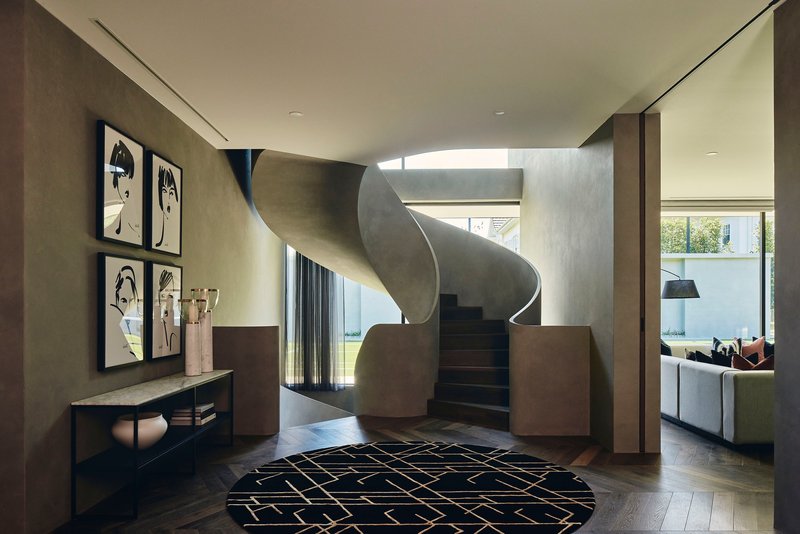 Sculptural spiral staircase in blackened steel rising through a skylit void in the entry hall