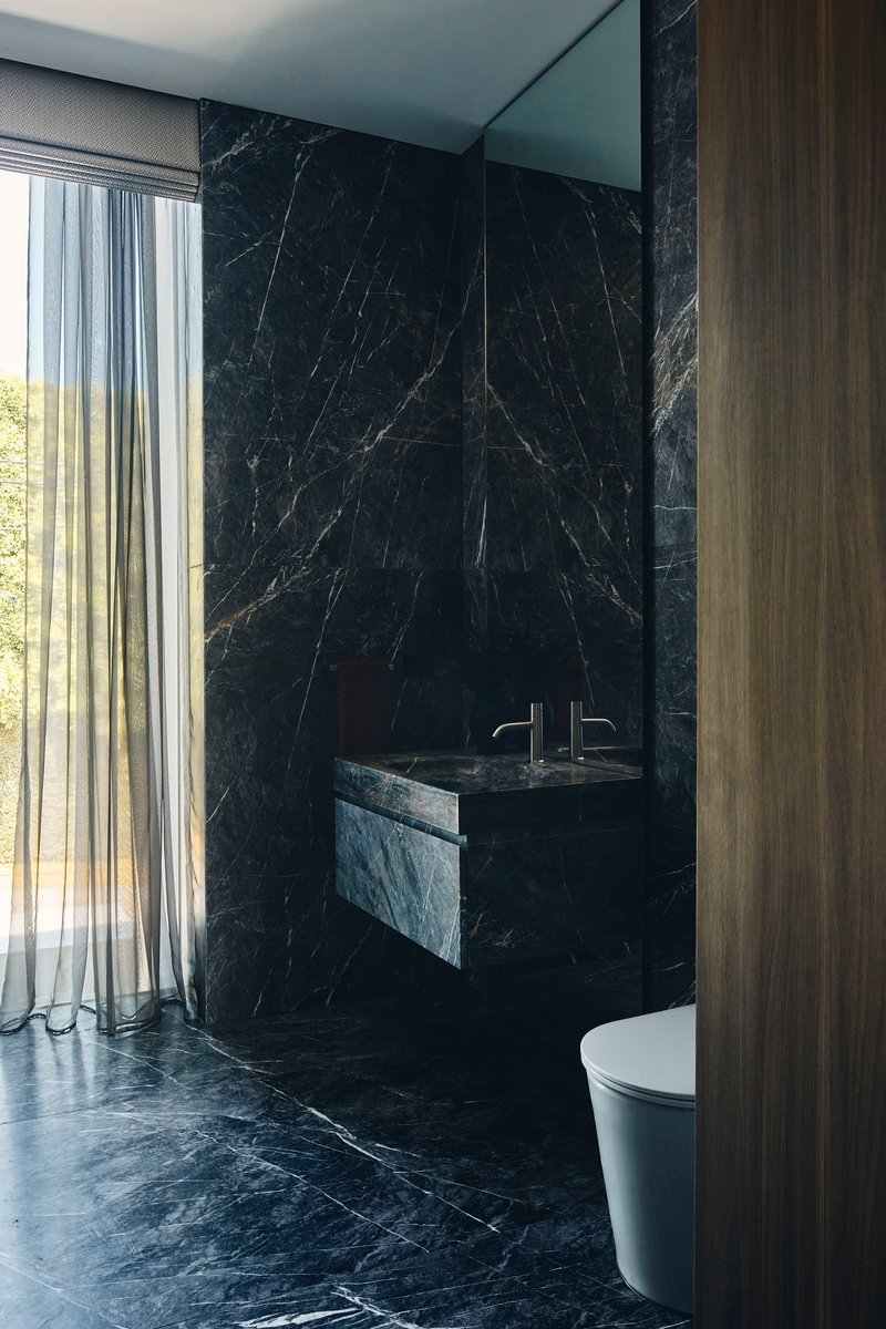 Bathroom with black marble walls, floating sink, and sheer curtains revealing trees outside