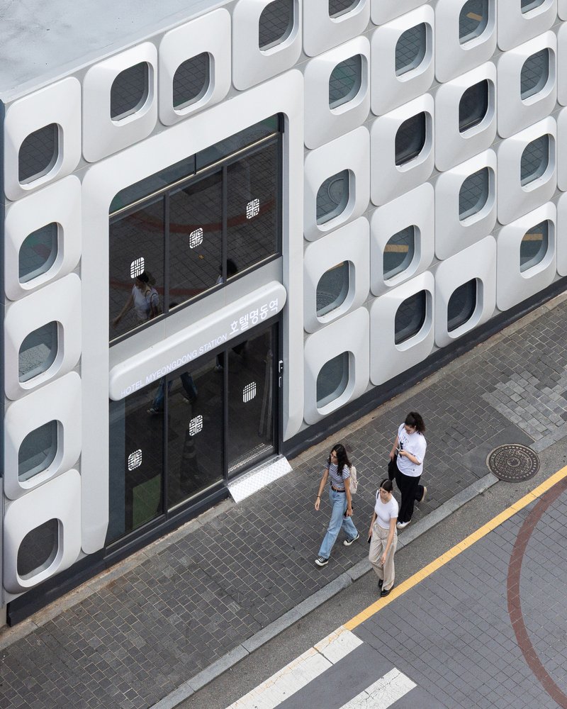Elevated view of the entrance canopy and three pedestrians walking along the sidewalk below