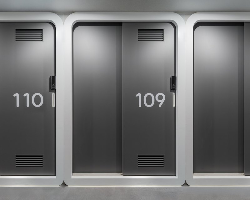 Row of numbered grey sliding doors with ventilation grilles and white rounded frames