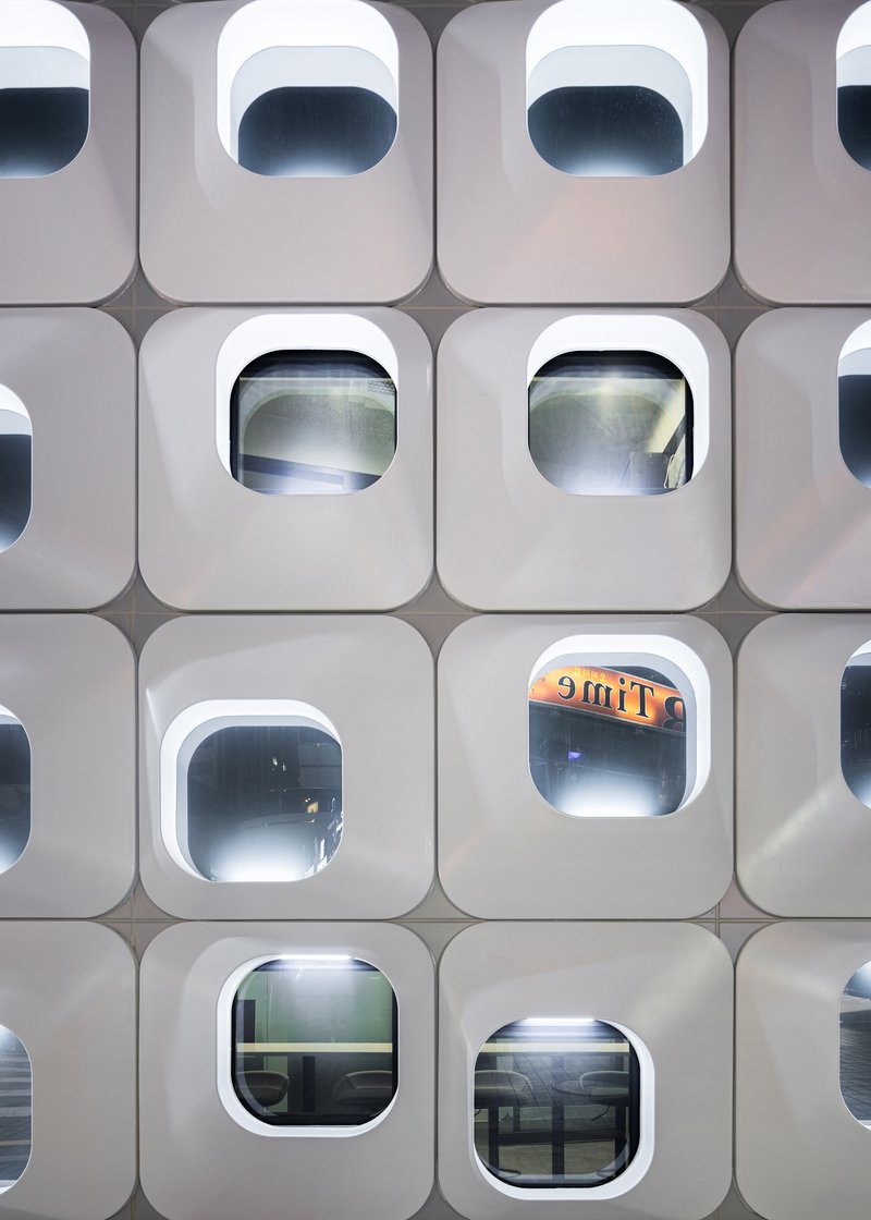 Close-up of the white facade panels showing the depth of the rounded window frames