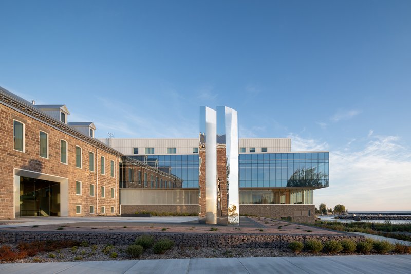 View across the planted courtyard showing the historic brick building alongside the glass and panel addition
