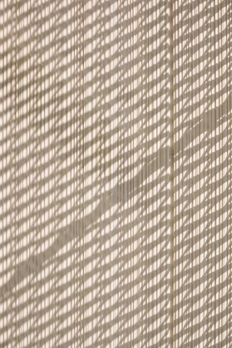 Dappled sunlight casting diagonal shadow patterns across a textured beige wall surface