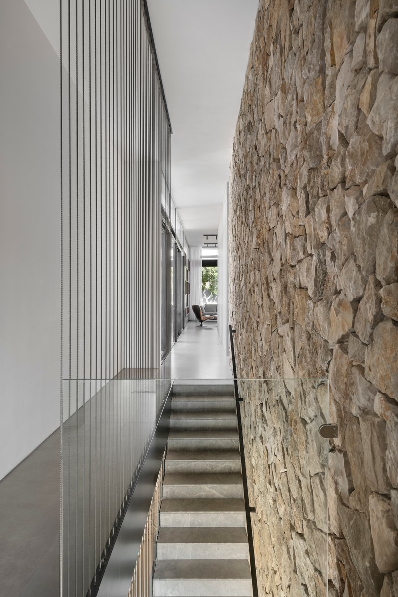Concrete stairs flanked by a rough stone wall and vertical timber battens in natural light