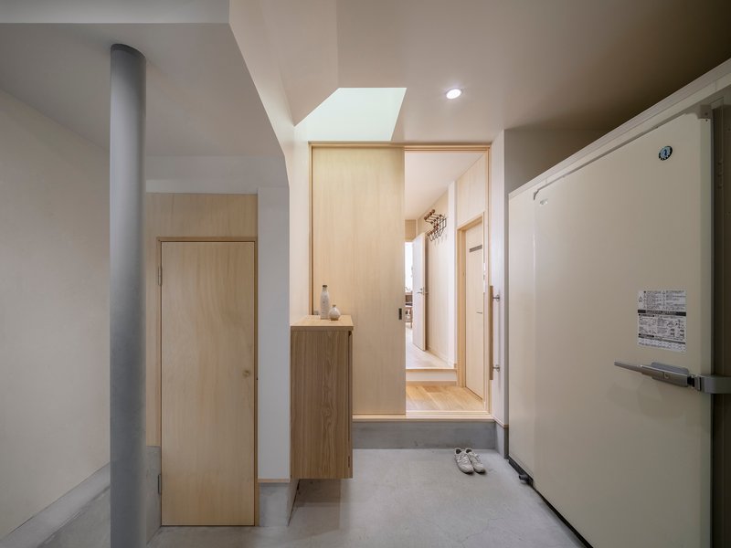 Entry corridor with concrete floor and skylight above the timber doorway and cabinet