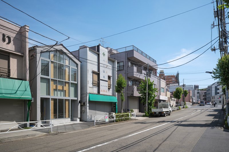 Perspective down the street showing the glazed facade among low-rise commercial and residential buildings