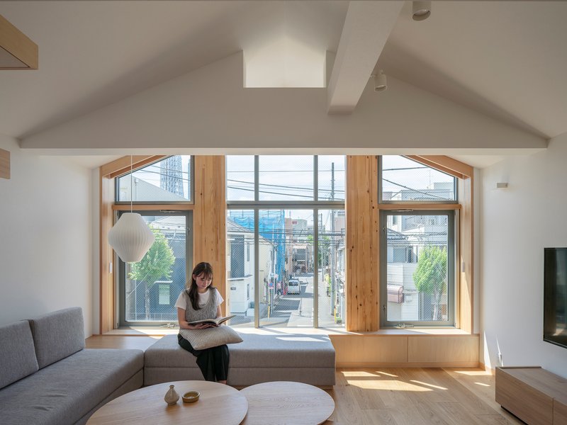 Living room with timber bay window framing street views and a resident reading on the seating platform