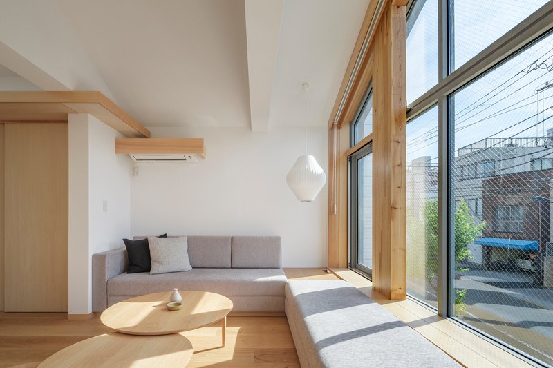 Living space with timber window frames casting afternoon sunlight across the floor and upholstered seating