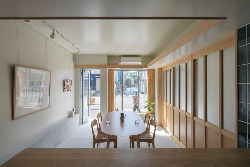 Interior dining area with timber screen partition and street-facing window framing a tree outside