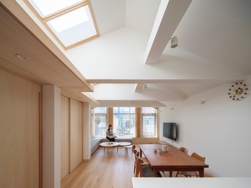 Open living space with timber-framed skylights and a seated figure by the window