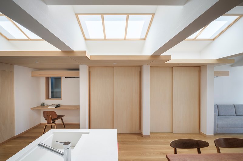 Living area ceiling with recessed timber-framed skylights between white structural beams