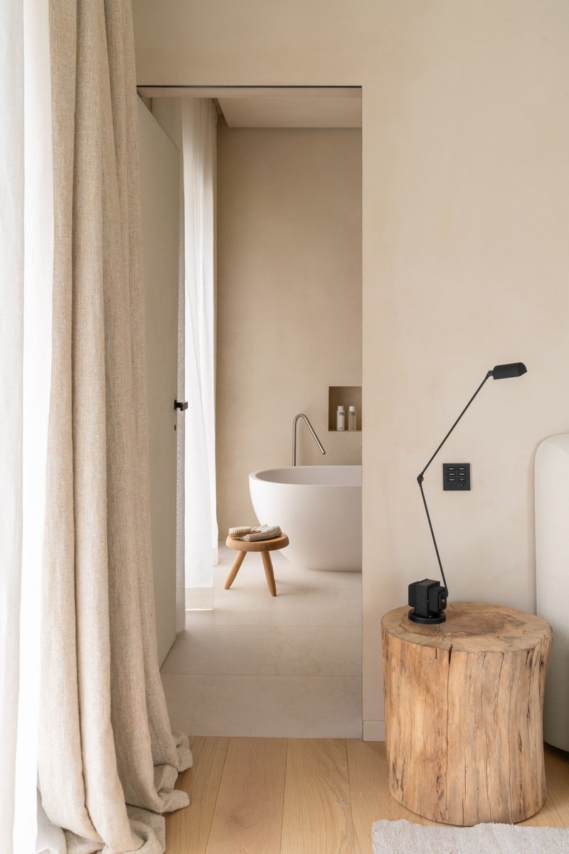View through doorway to bathroom with freestanding tub and raw timber stool