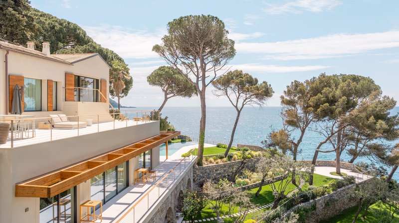 Terraced residence with timber canopy overhang and mature pine trees overlooking the sea