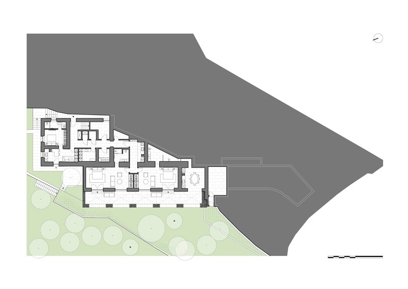 Floor plan drawing showing interior rooms and landscaped zones adjacent to a sloped site