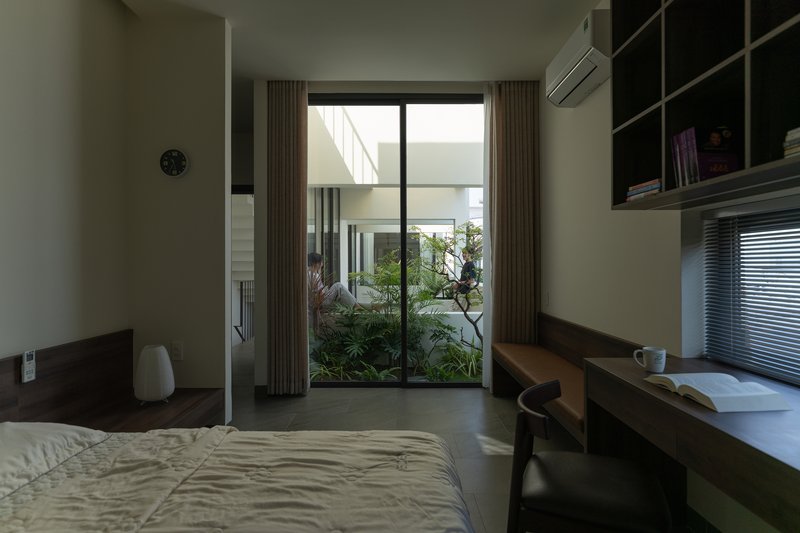 Bedroom with timber desk and glass doors opening to a small planted courtyard