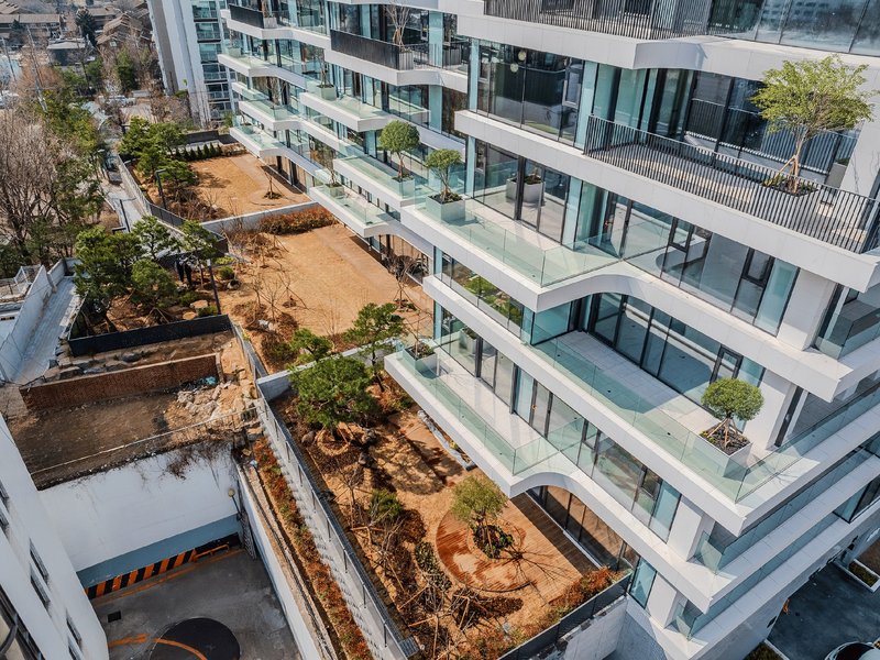 Aerial view of terraced courtyards with fresh soil, planted beds, and glass-edged balconies between buildings
