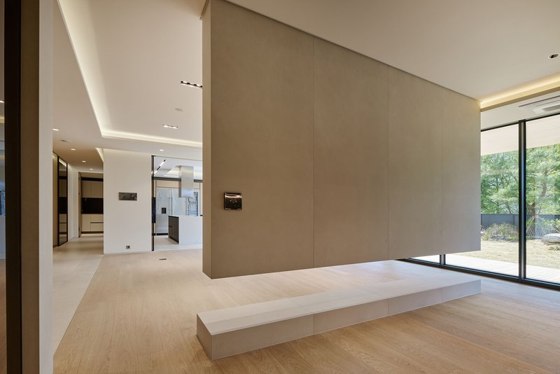 Interior entry space with pale wood flooring, recessed ceiling cove lighting and full-height glazing to the garden