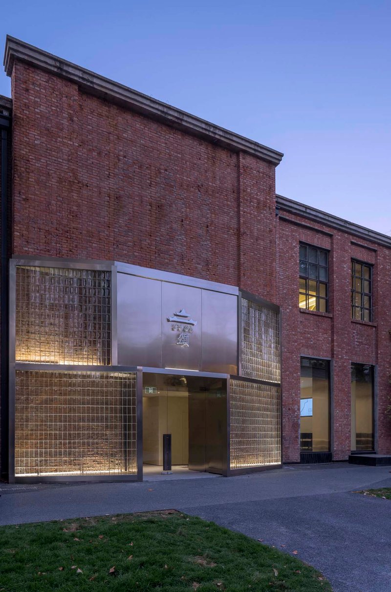 Brick facade with glass brick panels and illuminated entrance at dusk