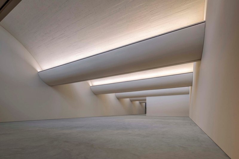 Interior gallery space with stepped ceiling coffers and recessed lighting over polished concrete floor