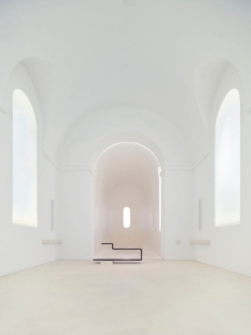 View toward the altar with cantilevered black steel platform beneath rounded apse window