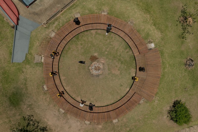Aerial view of the ring-shaped timber deck with visitors seated on benches around the perimeter