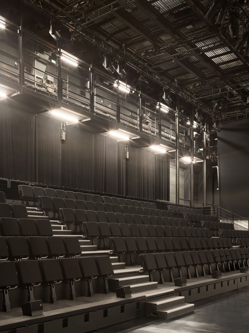 Angled view of the raked seating rows with stage curtains and suspended lighting infrastructure