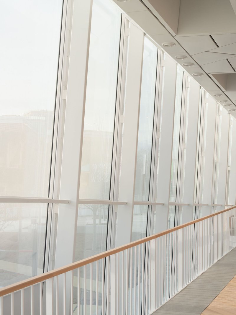 Corridor with floor-to-ceiling glazing and vertical white balusters in overcast daylight