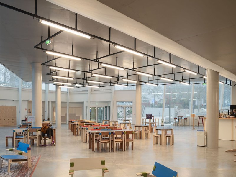 Dining area with timber tables and chairs under geometric linear lighting fixtures