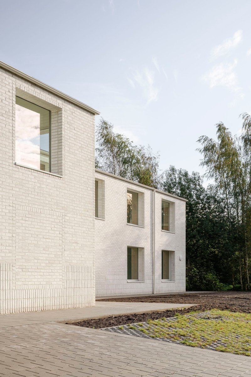 White brick facade with recessed window frames and vertical brick detailing alongside a timber deck