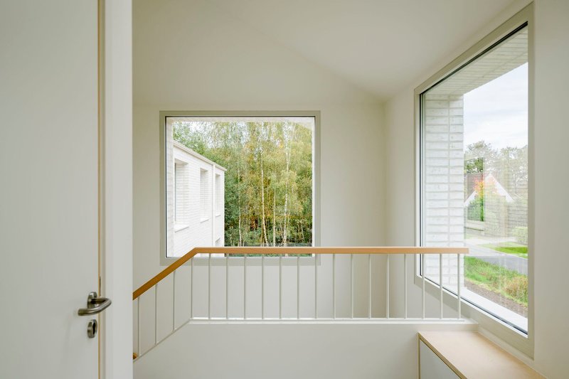 Upper landing with timber handrail and corner windows framing neighboring gabled roofline